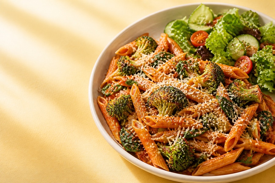 Penne pasta with roasted broccoli in tomato sauce.